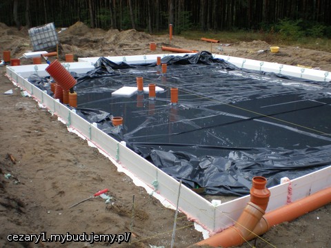 po ustawieniu i połączeniu cokołów szalunku traconego i po ułożeniu dwóch warstw folii hydroizolacyjnej o średniej sztywności,  łączonej na 15cm zakład uszczelniaczem dekarskim i wywiniętej na cokoły styropianowe szalunku traconego płyty fundamentowej.