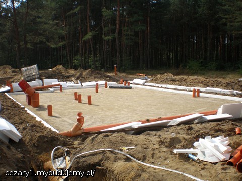 przed ułożeniem cokołów ze styropianu 15cm grubości EPS 100, wcześniej odpowiednio sfazowanych/przyciętych we własnym zakresie (taniej) maszynką z drutem oporowym i z wyfrezowanymi na frezarce do drewna z boków rowkami na łączniki styopianowe (docięte uprzednio na pile do drewna). ułożone i połączone z użyciem kleju do styropianu w sprayu cokołu na następnym zdjęciu.