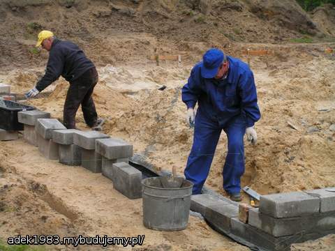Tatusiowie murują fundamenty z bloczków.
